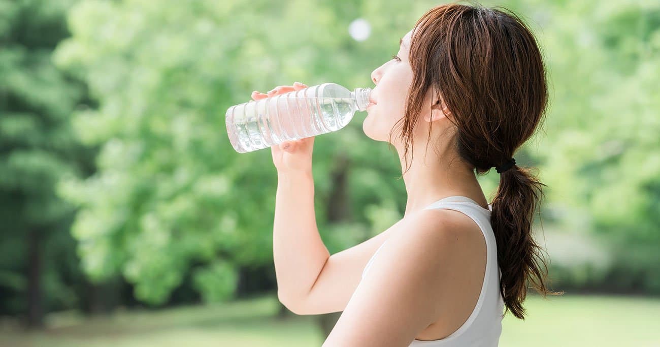 ペットボトルから水を飲む女性